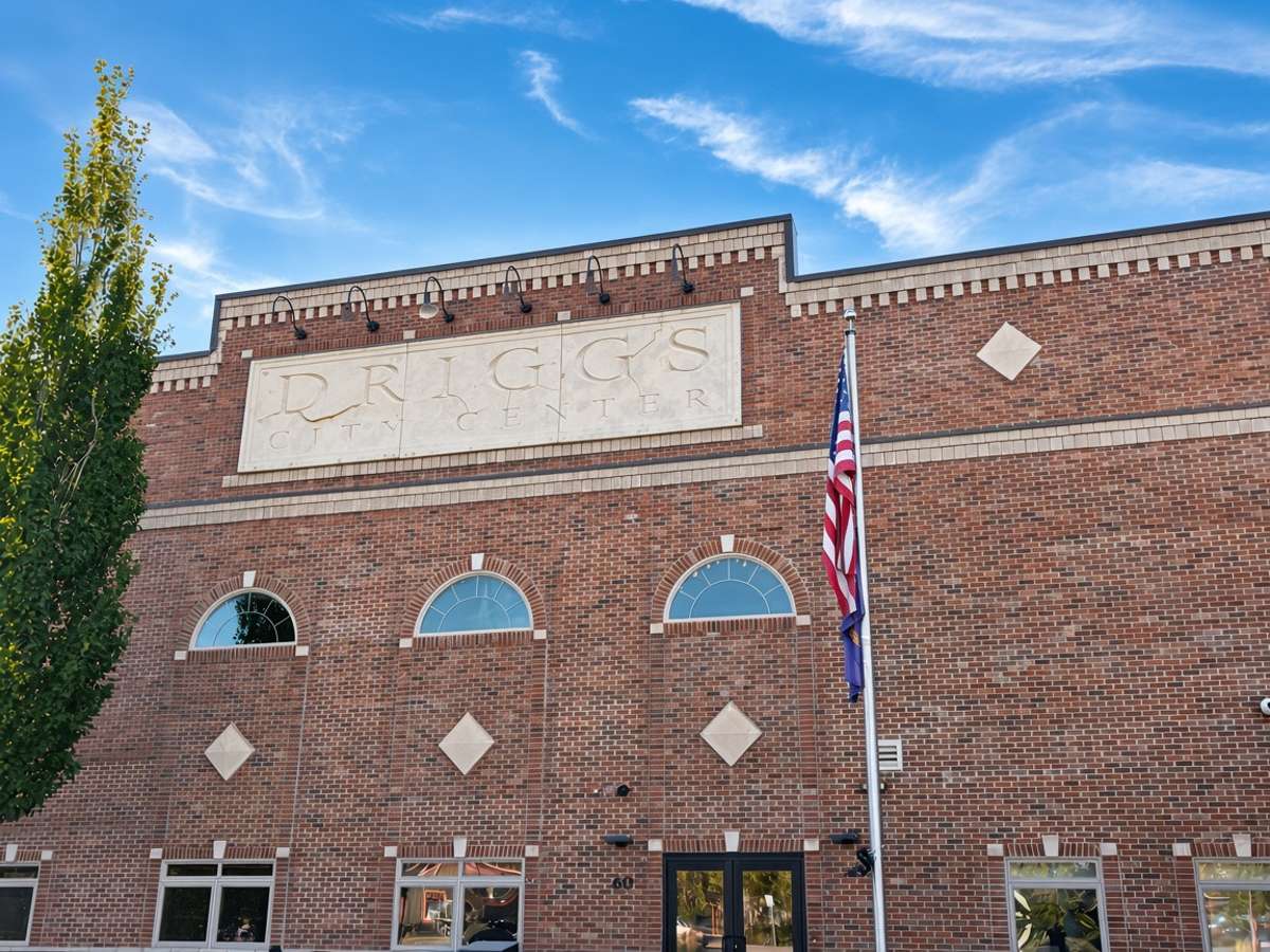 Brick facade of the Driggs City Center, its name carved above arched windows, with an American flag out front
