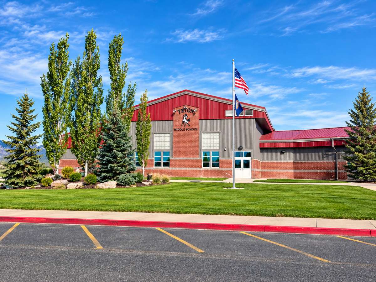Teton Middle School's red-roofed brick building with flags flying out front on a sunny day