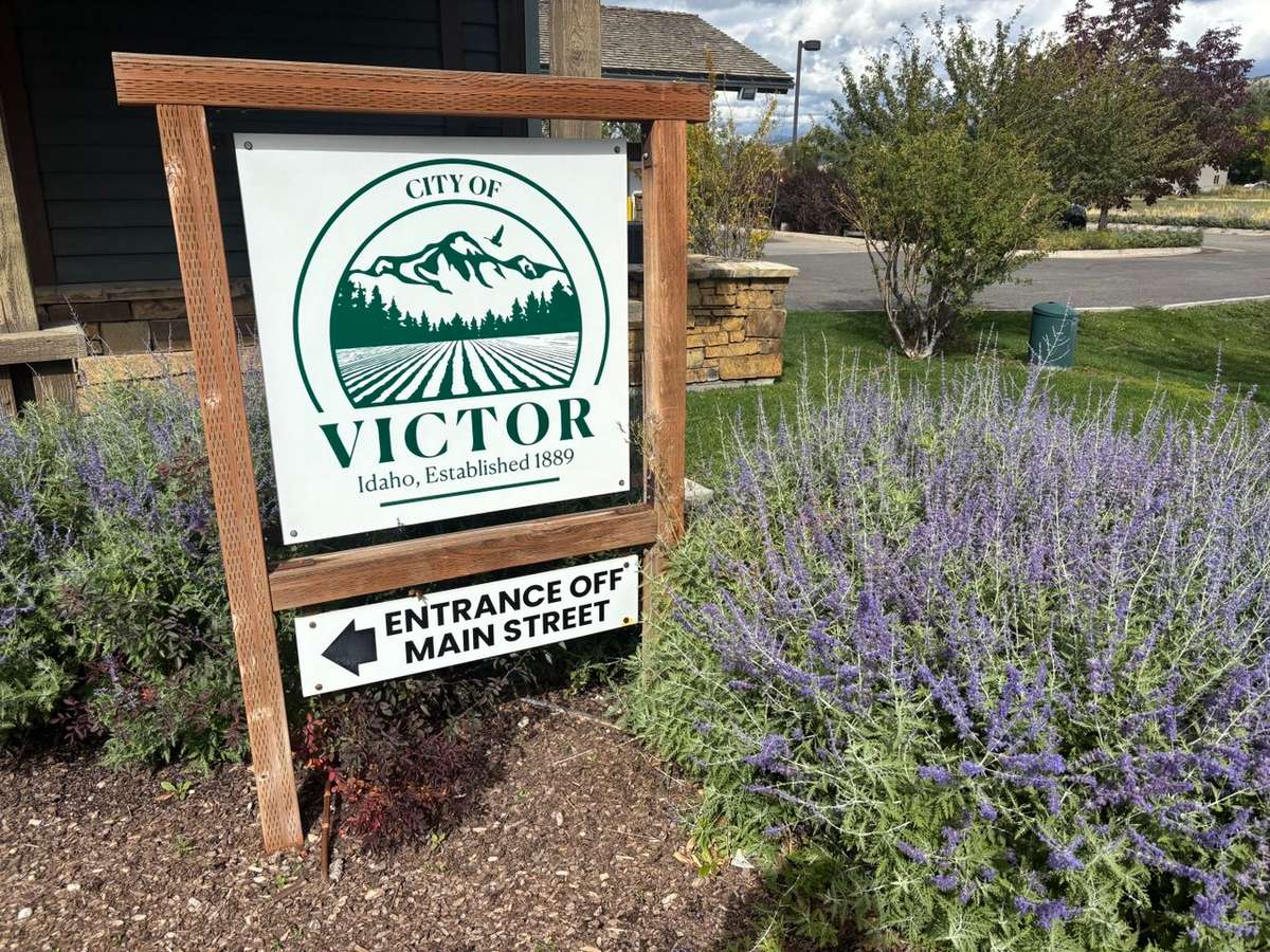 City of Victor sign, "Idaho, Established 1889," with an arrow to the entrance off Main Street, beside lavender shrubs